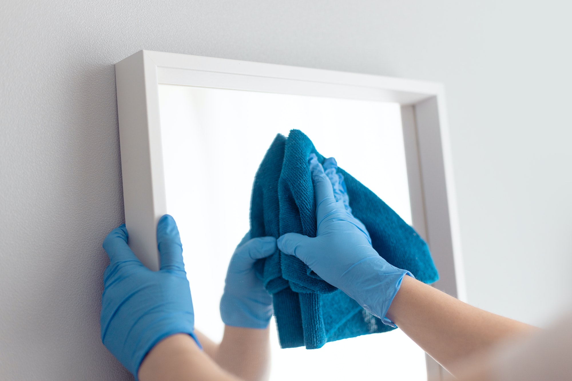 Woman cleaning mirror with rag. Housemaid cleaning at home